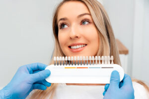 a woman smiling getting her teeth checked for color matching on her veneers