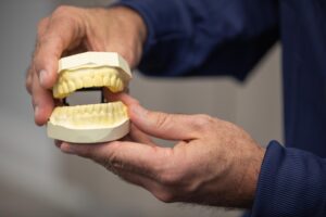 Dr. Ashton holding a dental implant model.